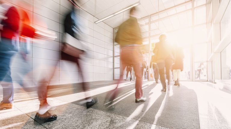 People walking in a brightly lit office lobby, highlighting the importance of employee security and awareness programs.